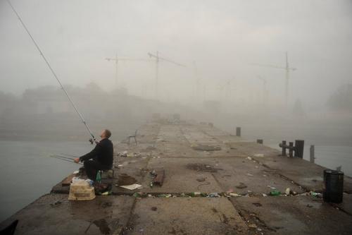 Homem pesca em dique próximo às instalações olímpicas / Foto: Mikhail Mordasov
